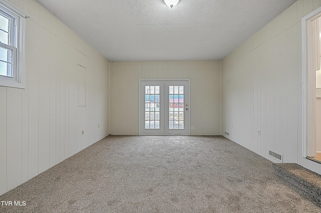 empty room with wooden walls, a textured ceiling, and carpet