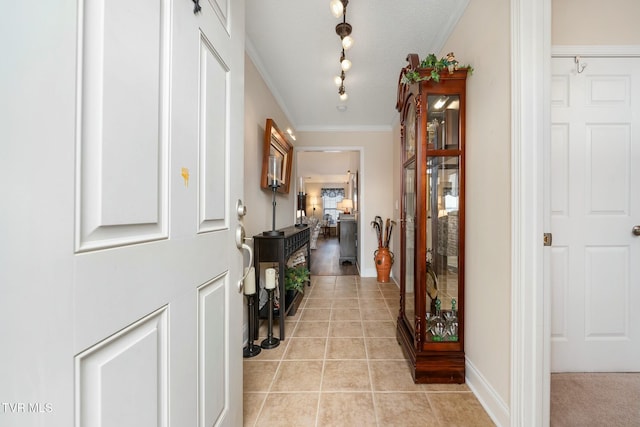 corridor featuring light tile patterned flooring, ornamental molding, and track lighting