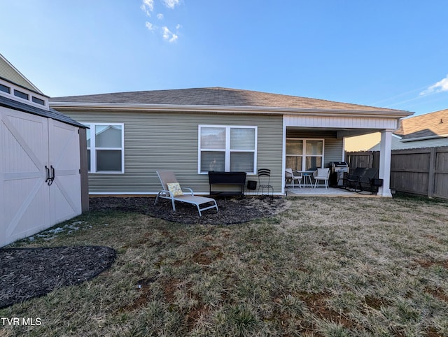 rear view of property featuring a storage shed, a patio, and a yard