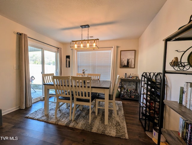 dining space with dark wood-type flooring and an inviting chandelier