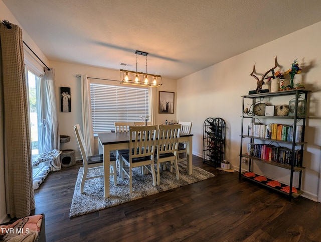 dining area with dark hardwood / wood-style floors, an inviting chandelier, and a textured ceiling