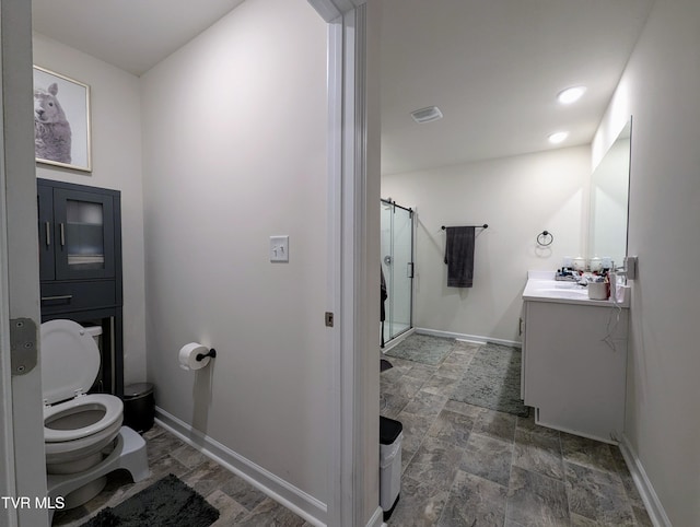 bathroom featuring toilet, a shower with shower door, and vanity