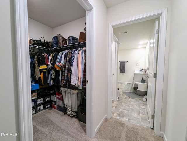 walk in closet with light colored carpet