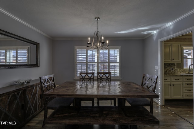 dining space with sink, an inviting chandelier, a textured ceiling, ornamental molding, and dark wood-type flooring