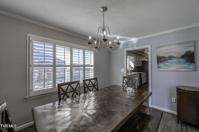 dining area with dark wood-type flooring, a textured ceiling, a notable chandelier, ornamental molding, and sink