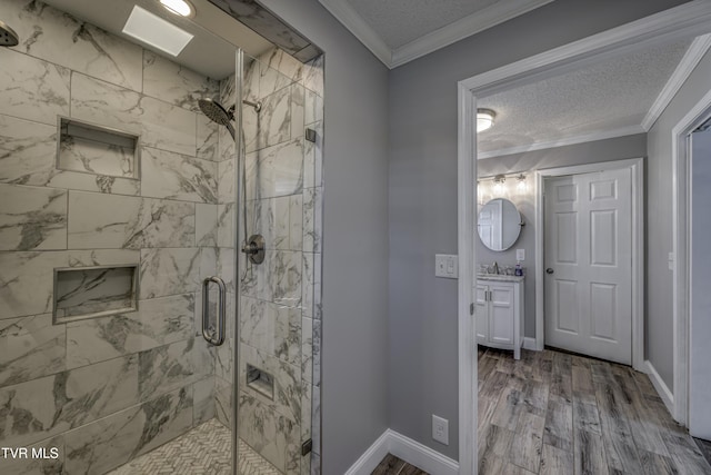 bathroom featuring wood-type flooring, walk in shower, crown molding, vanity, and a textured ceiling