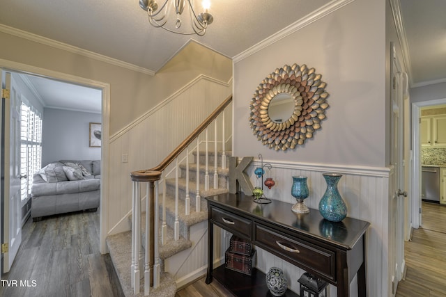 stairway with ornamental molding, hardwood / wood-style flooring, and a notable chandelier