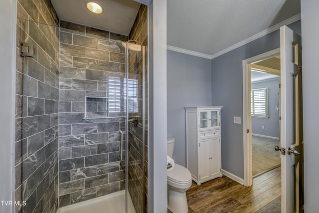 bathroom with wood-type flooring, crown molding, a tile shower, and toilet