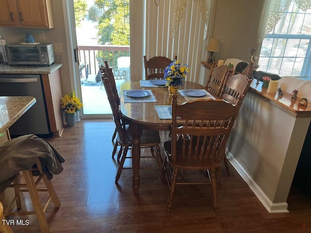 dining room featuring baseboards, plenty of natural light, dark wood finished floors, and a toaster