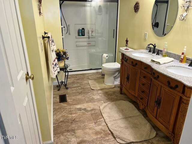 full bathroom with a sink, a shower stall, toilet, and double vanity