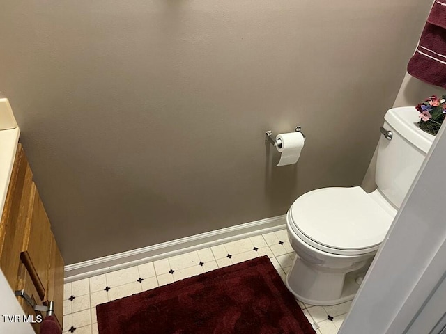 half bathroom with toilet, tile patterned flooring, and baseboards