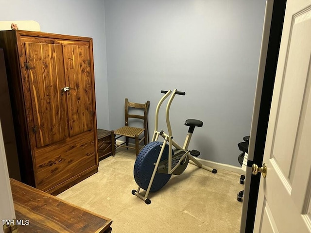 exercise area featuring light carpet and baseboards