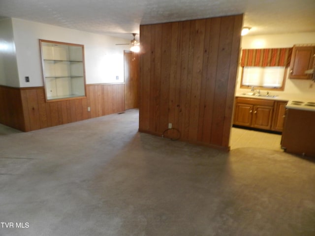 unfurnished living room with sink, wooden walls, ceiling fan, and built in features