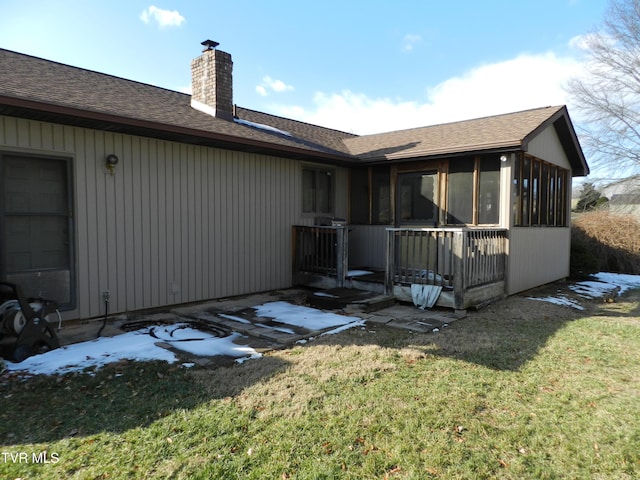 back of house featuring a lawn and a sunroom