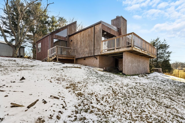 snow covered back of property featuring a deck