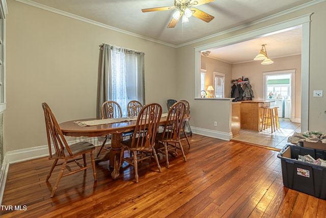 dining room with hardwood / wood-style floors, washer / dryer, ornamental molding, and ceiling fan