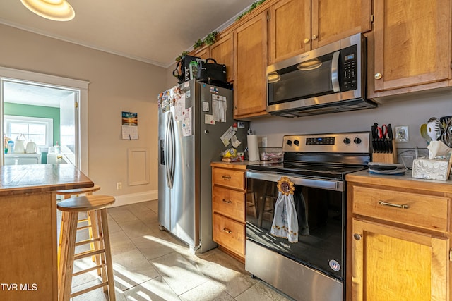 kitchen featuring stainless steel appliances, ornamental molding, and light tile patterned floors