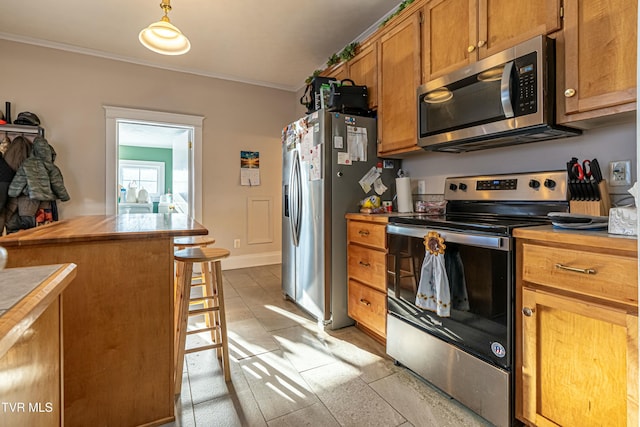 kitchen featuring stainless steel appliances, crown molding, a kitchen bar, and decorative light fixtures