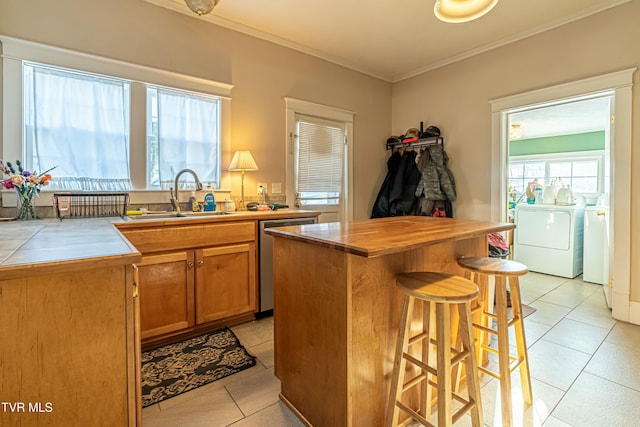 kitchen with sink, a center island, light tile patterned floors, dishwasher, and washing machine and dryer