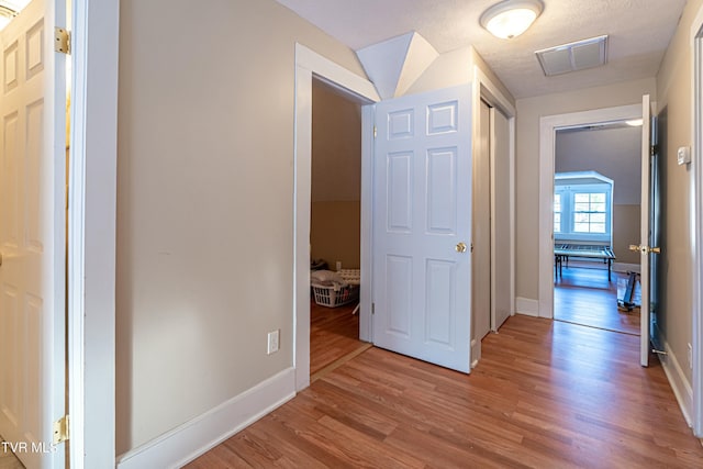 hallway with light hardwood / wood-style floors and a textured ceiling