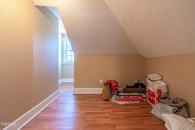 bonus room featuring lofted ceiling, a textured ceiling, and light wood-type flooring