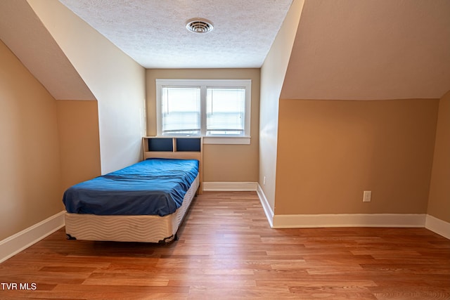 bedroom with hardwood / wood-style flooring and a textured ceiling