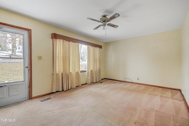 carpeted empty room with ceiling fan and a wealth of natural light