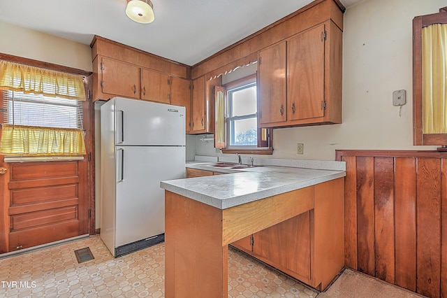 kitchen featuring kitchen peninsula, sink, and white refrigerator