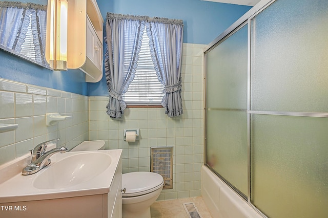 full bathroom with toilet, tile walls, tile patterned floors, and shower / bath combination with glass door