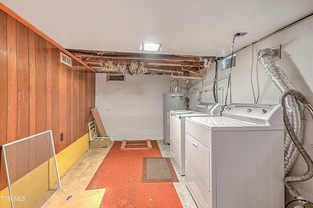 washroom featuring separate washer and dryer, electric water heater, and wood walls