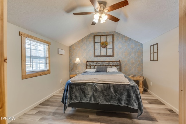 bedroom featuring ceiling fan, a textured ceiling, hardwood / wood-style flooring, and vaulted ceiling