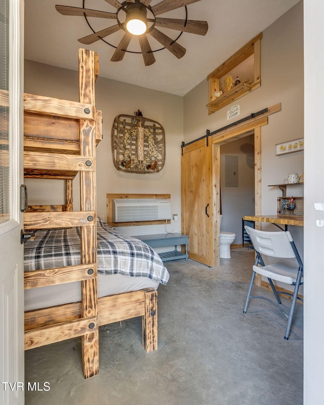 bedroom with ceiling fan, a barn door, a wall mounted air conditioner, connected bathroom, and concrete flooring