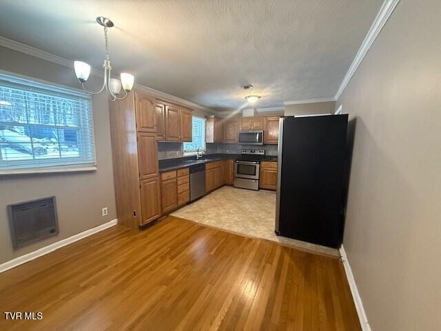 kitchen featuring a notable chandelier, sink, stainless steel appliances, and ornamental molding