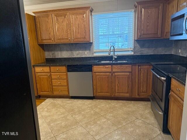 kitchen featuring light tile patterned floors, sink, appliances with stainless steel finishes, and dark stone countertops