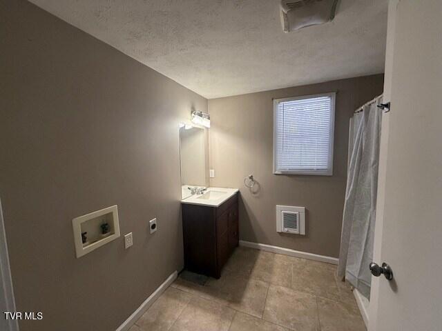 bathroom with a textured ceiling, heating unit, vanity, and curtained shower