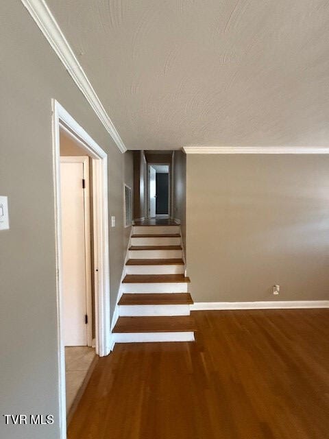 stairway with wood-type flooring and ornamental molding