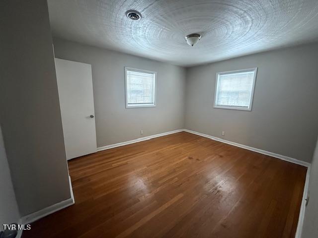 spare room featuring a wealth of natural light and hardwood / wood-style floors