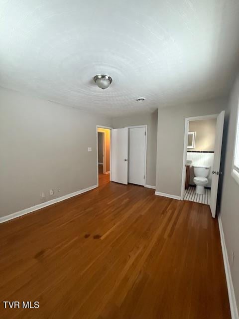 unfurnished bedroom featuring connected bathroom and hardwood / wood-style floors