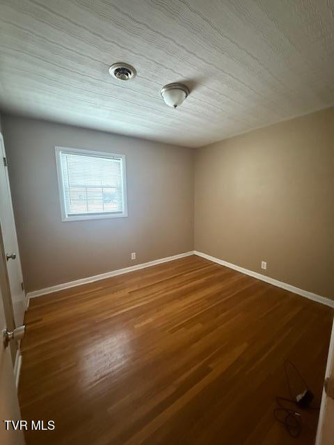 spare room featuring a textured ceiling and hardwood / wood-style flooring