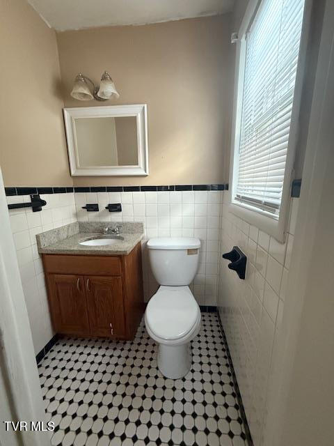 bathroom with tile patterned flooring, vanity, tile walls, and toilet