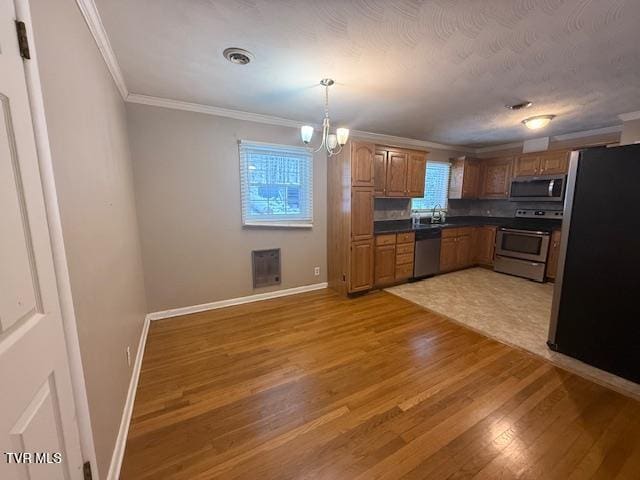 kitchen featuring an inviting chandelier, hardwood / wood-style flooring, hanging light fixtures, stainless steel appliances, and ornamental molding