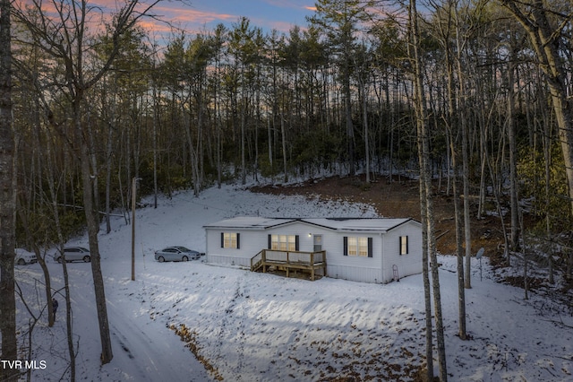 snow covered back of property featuring a wooden deck