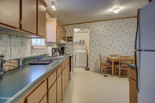 kitchen with electric range, separate washer and dryer, ornamental molding, white refrigerator, and sink