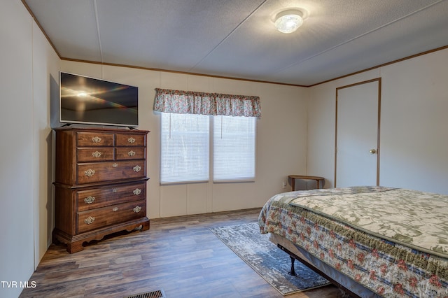 bedroom with ornamental molding, a textured ceiling, and hardwood / wood-style floors