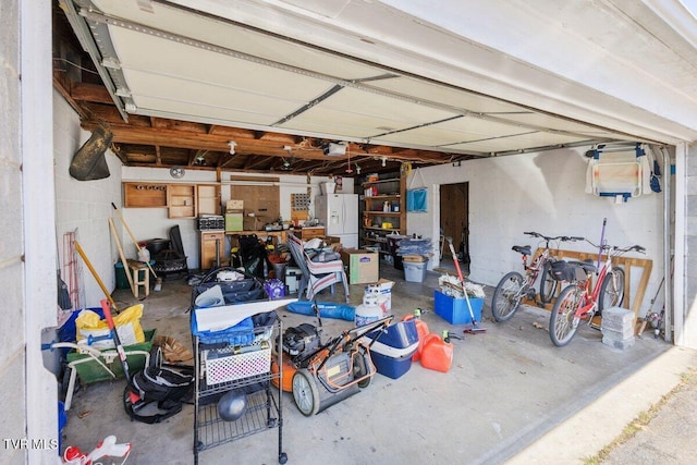 garage with a garage door opener and white fridge with ice dispenser