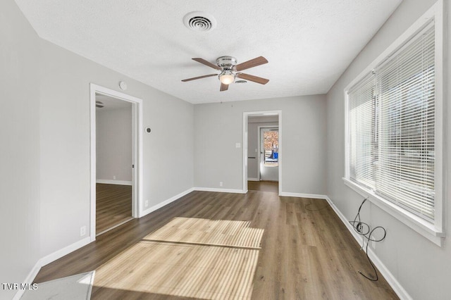 empty room featuring ceiling fan, a textured ceiling, and hardwood / wood-style flooring