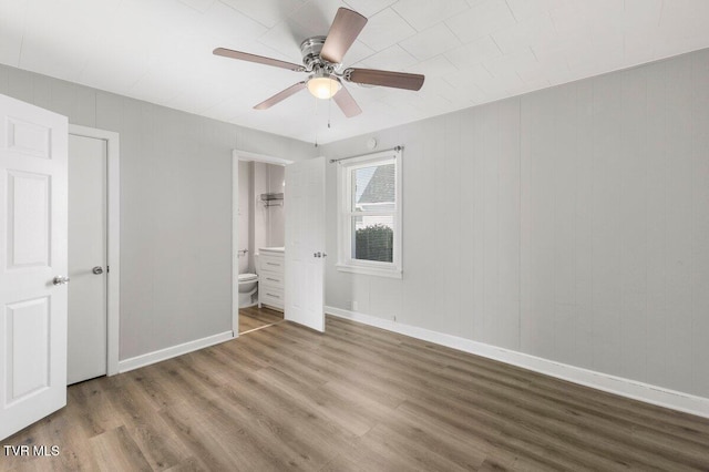 unfurnished bedroom with ceiling fan, ensuite bath, and wood-type flooring