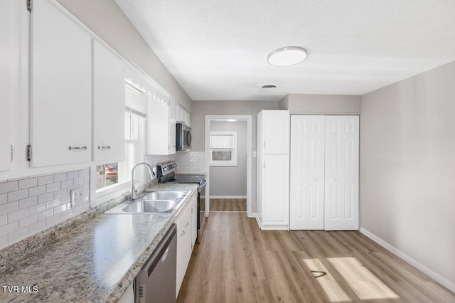 kitchen featuring tasteful backsplash, light hardwood / wood-style floors, sink, stainless steel appliances, and white cabinets