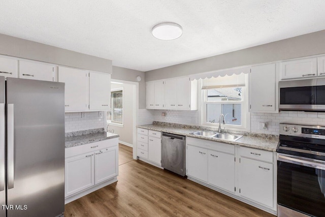 kitchen featuring a wealth of natural light, appliances with stainless steel finishes, white cabinets, and sink