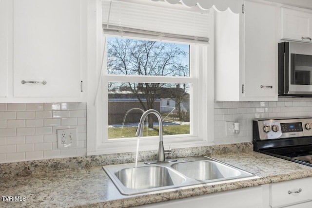 kitchen with white cabinets, stainless steel appliances, decorative backsplash, sink, and plenty of natural light